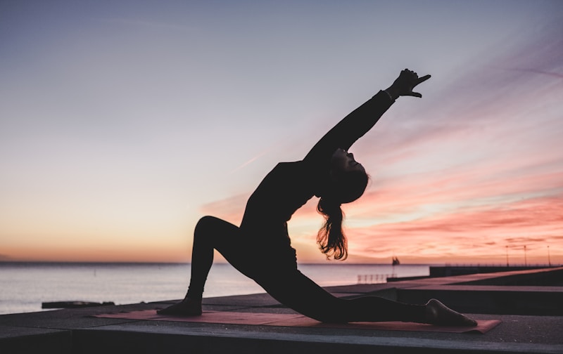 Person practicing gentle stretching outdoors in a peaceful natural setting